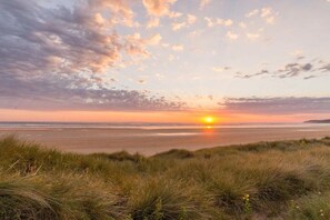 Un capvespre sobre una platja amb dunes al primer pla.