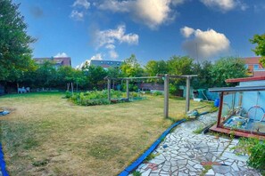 A backyard with a garden, a pergola, and a glass enclosure. - In the house Sommergarten 2 (Norderney)