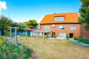 A two-story brick house with a tiled roof, a fenced backyard, and a small garden area. - In the house Sommergarten 2 (Norderney)