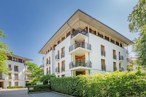 Ein mehrstöckiges Wohngebäude mit Balkonen, einem gepflasterten Innenhof und üppigem Grün.