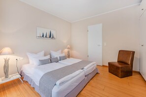 Ein Schlafzimmer mit einem Bett, Nachttischlampen, einem Sessel und einem Bild an der Wand.