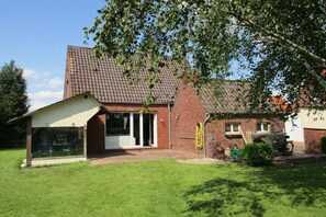 A two-story house with a brick exterior, a covered porch, and a well-maintained lawn. - Holiday home in Emden with swimming pool (Emden)