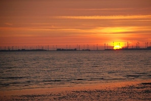A sunset over a body of water with wind turbines in the distance. - Holiday home in Emden with swimming pool (Emden)