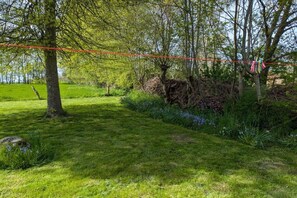 Ein grünes Areal im Freien mit Bäumen und einer roten Seilsperre.