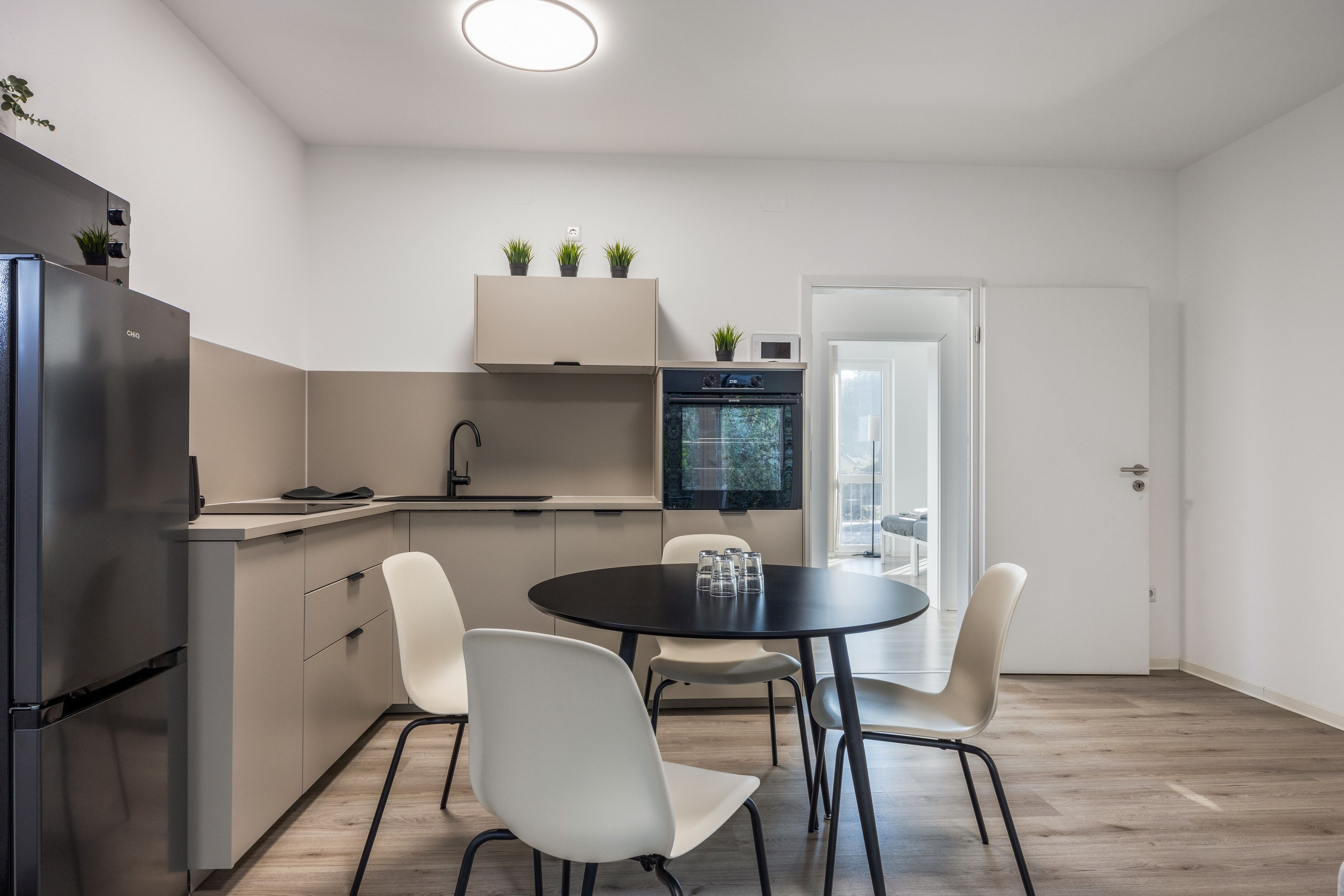 Eine moderne Küche mit Backofen, einem Esstisch mit Stühlen und einem Kühlschrank.