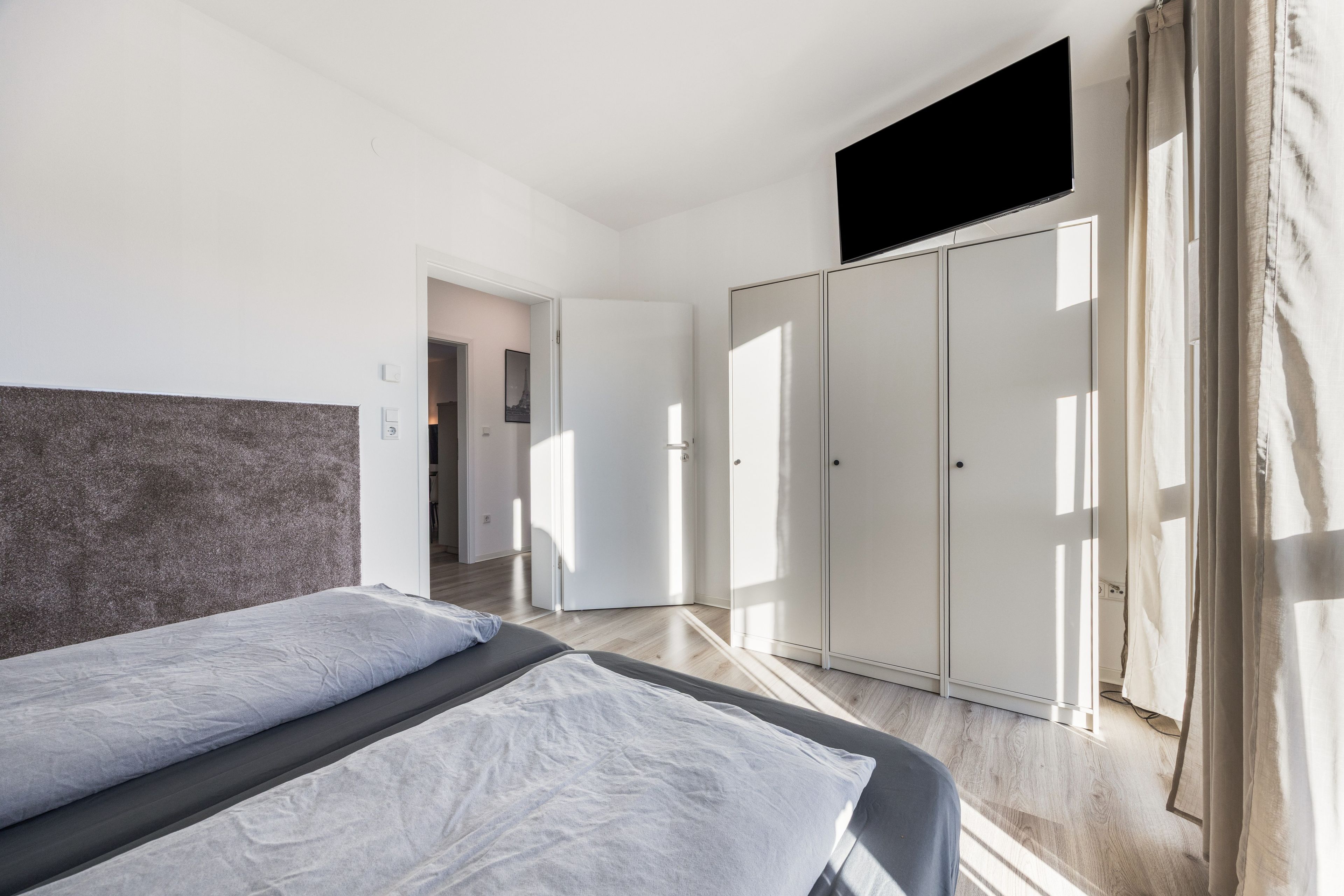 Ein modernes Schlafzimmer mit Bett, Kleiderschrank und Fernseher.