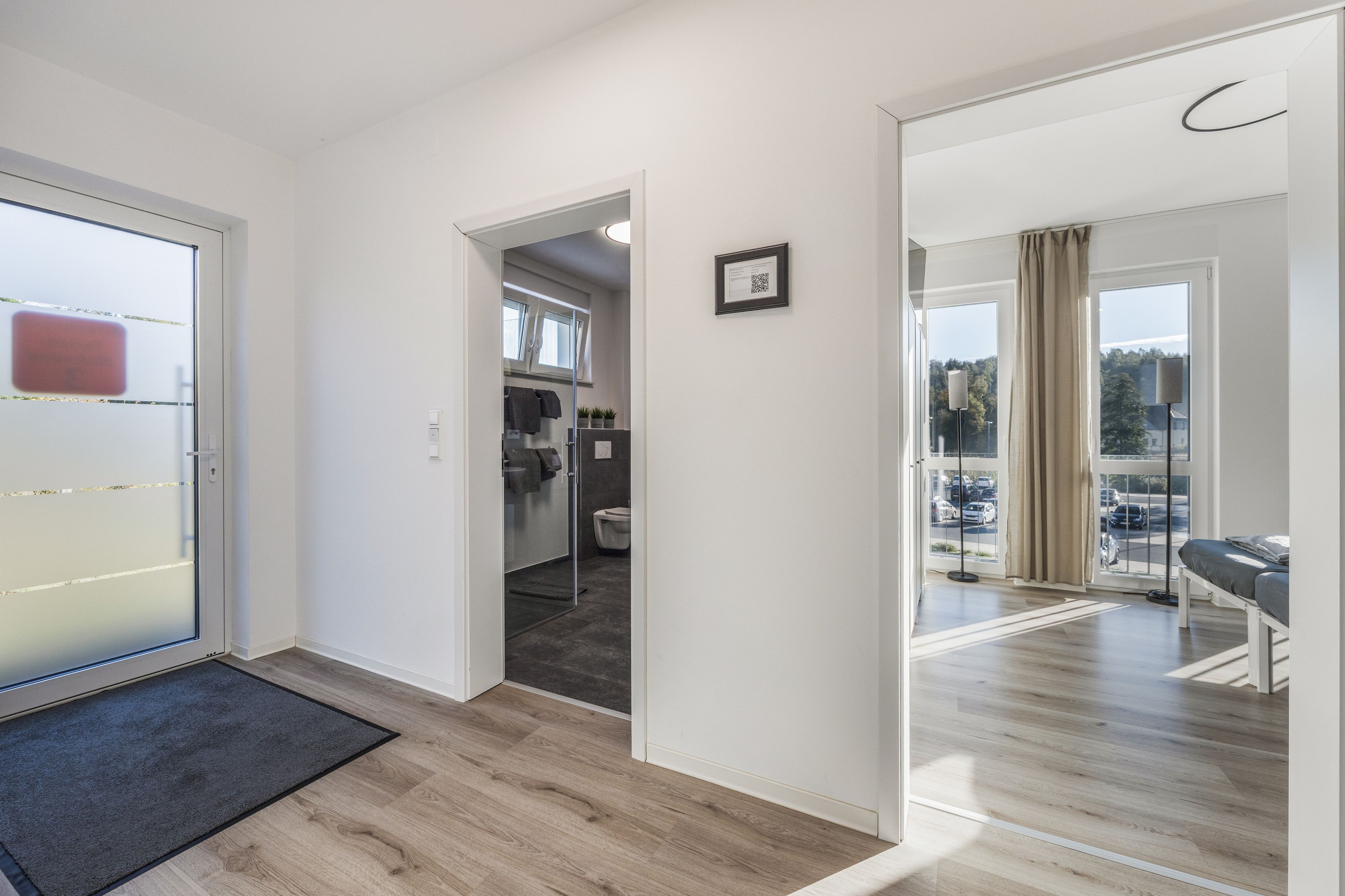 Ein modernes Hotelzimmer mit Holzboden, einem Balkon mit Blick und einem separaten Badebereich.