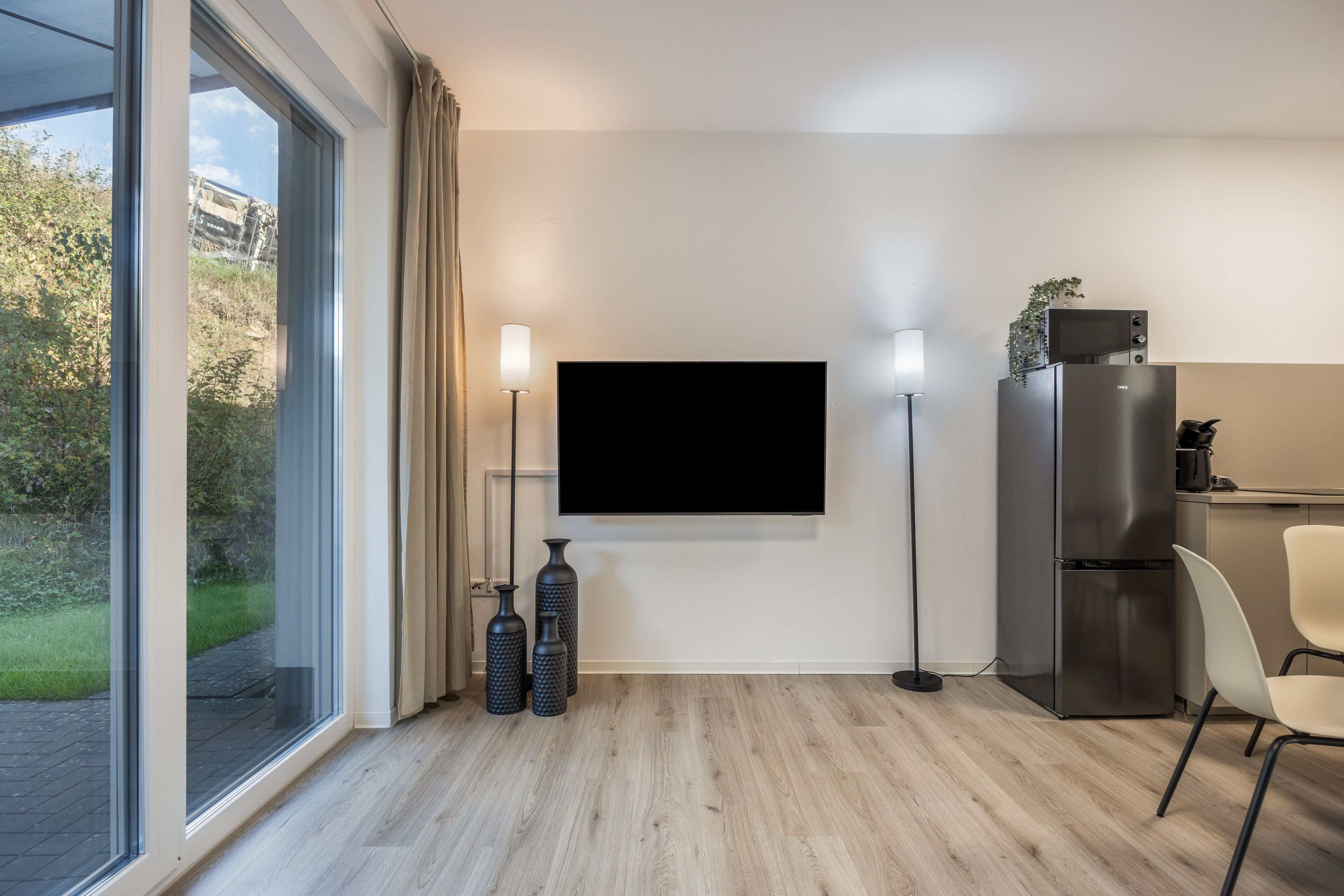 Eine moderne Küche mit Fernseher, Kühlschrank und Essbereich mit einem Stuhl.