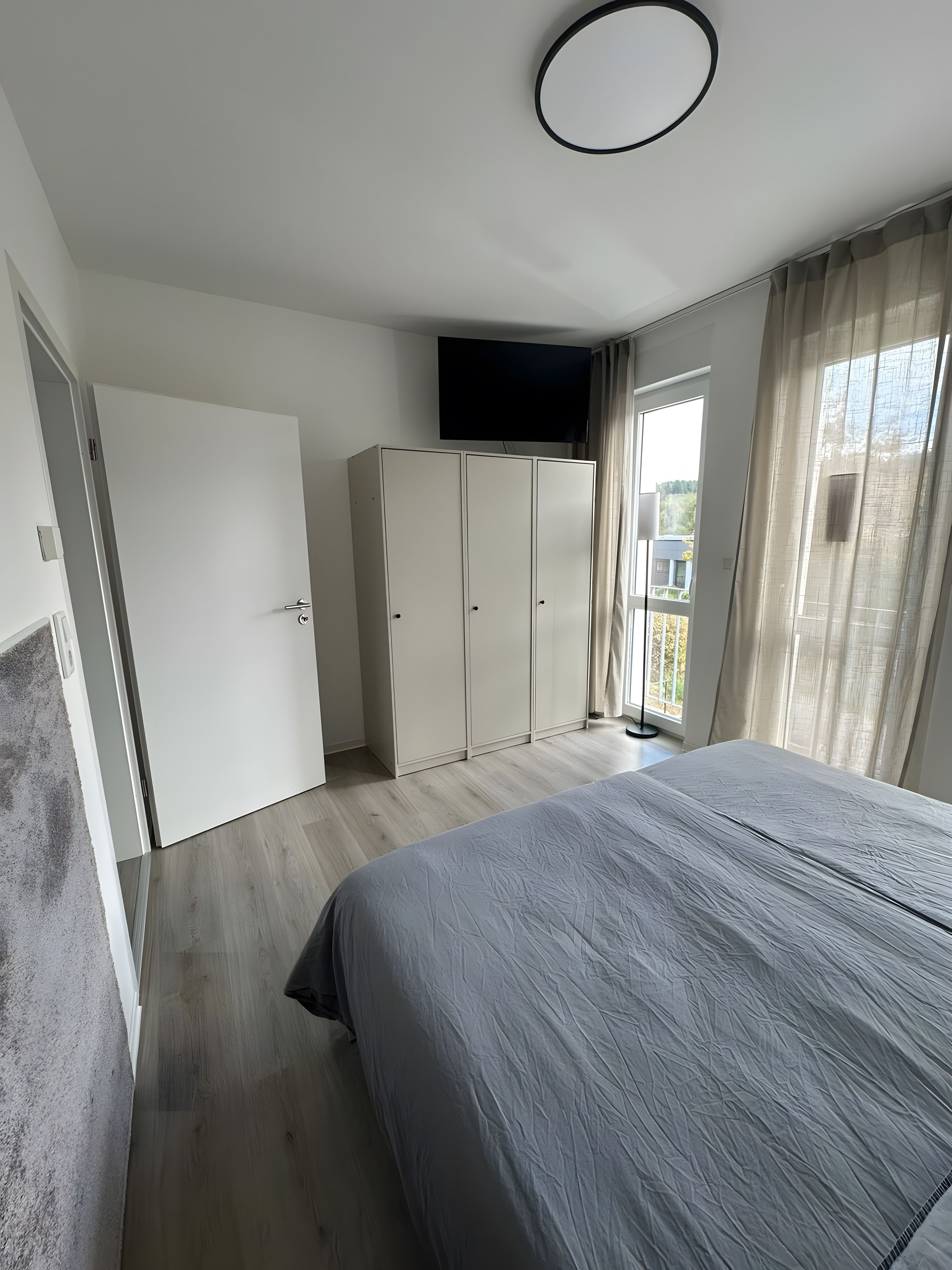 Ein Schlafzimmer mit Bett, Kleiderschrank und einem an der Wand befestigten Fernseher.