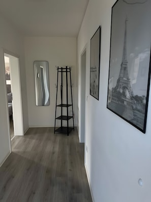 Ein Zimmer mit Holzboden, einem Kleiderhaken und zwei gerahmten Bildern an der Wand.