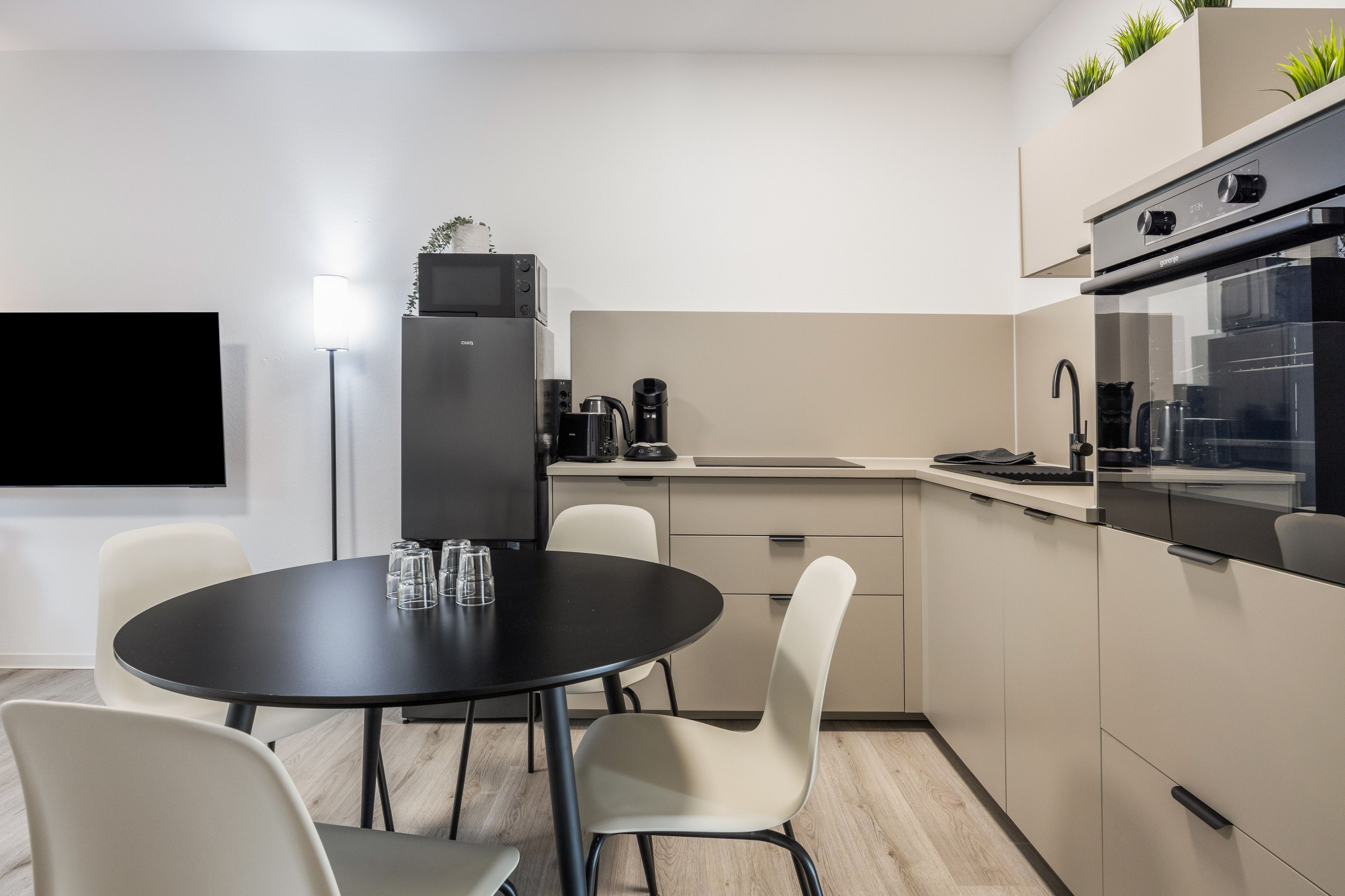 Eine moderne Küche mit einem schwarzen Esstisch, weißen Stühlen und einem eingebauten Backofen.