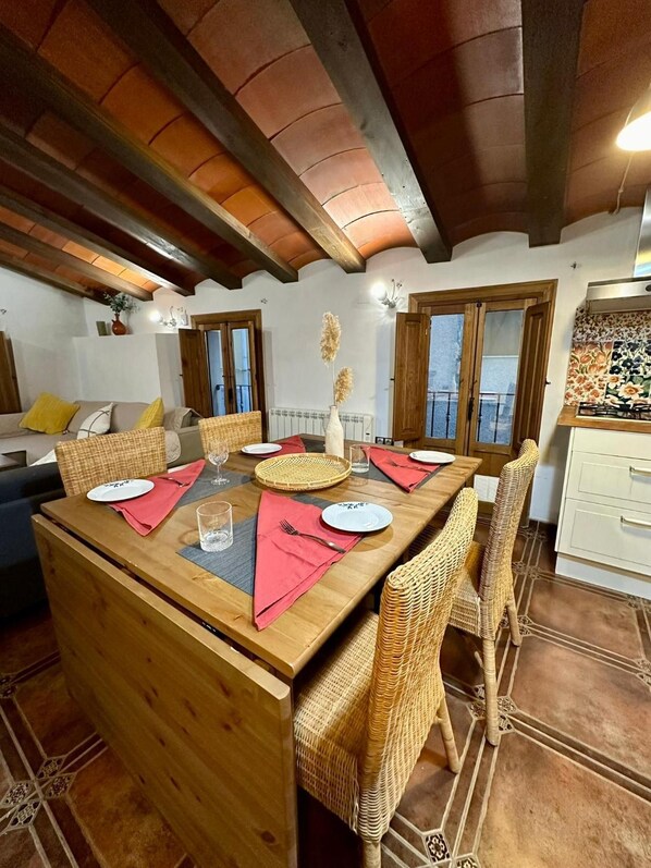 A dining area with a wooden table, wicker chairs, and a view of the outdoors through a window.
