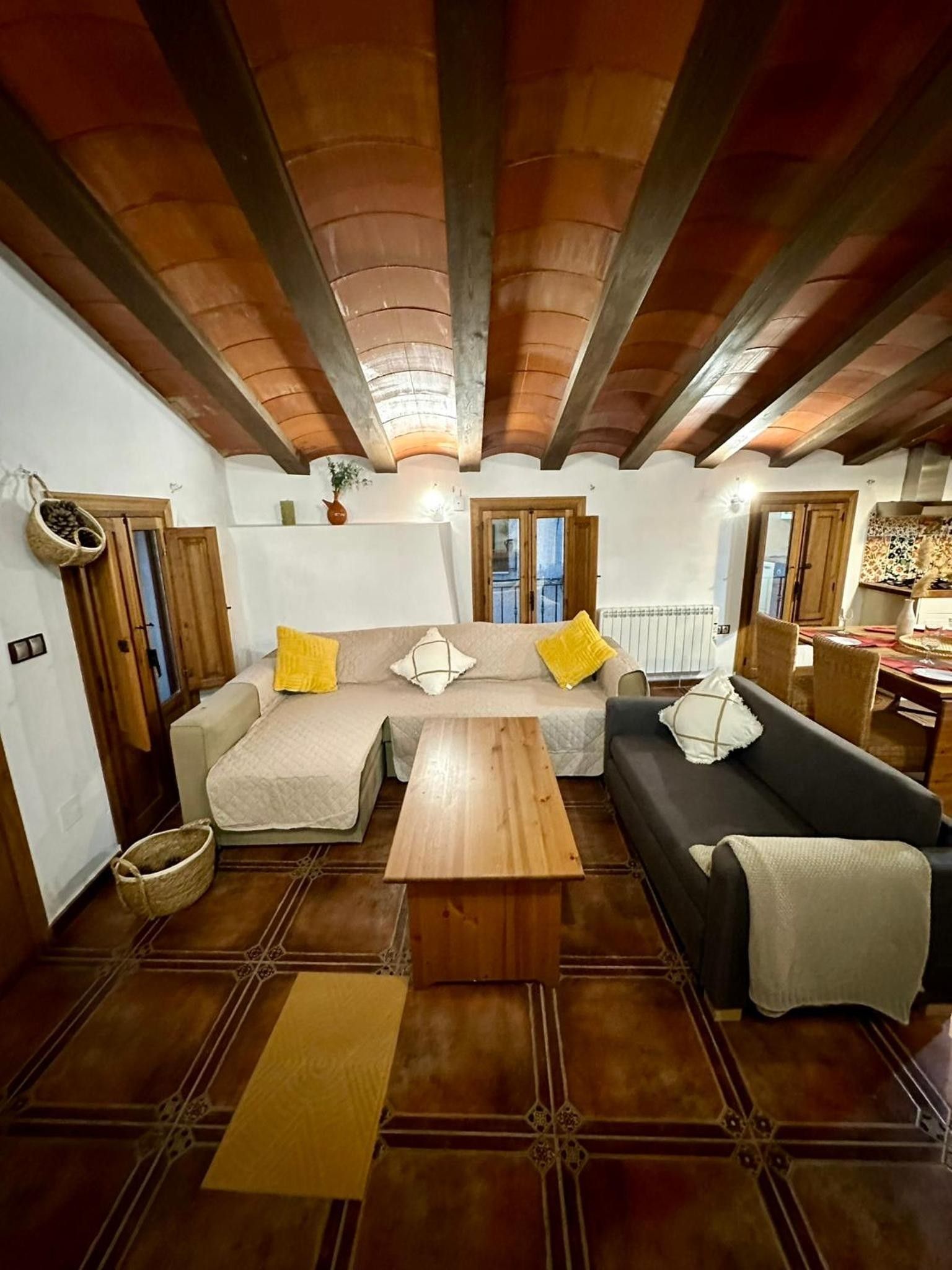 Una sala de estar con techo de madera, un juego de sofá, una mesa de centro y un comedor con mesa y sillas.