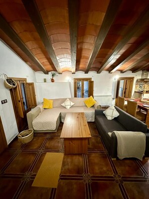 Una sala de estar con techo de madera, un juego de sofá, una mesa de centro y un comedor con mesa y sillas.