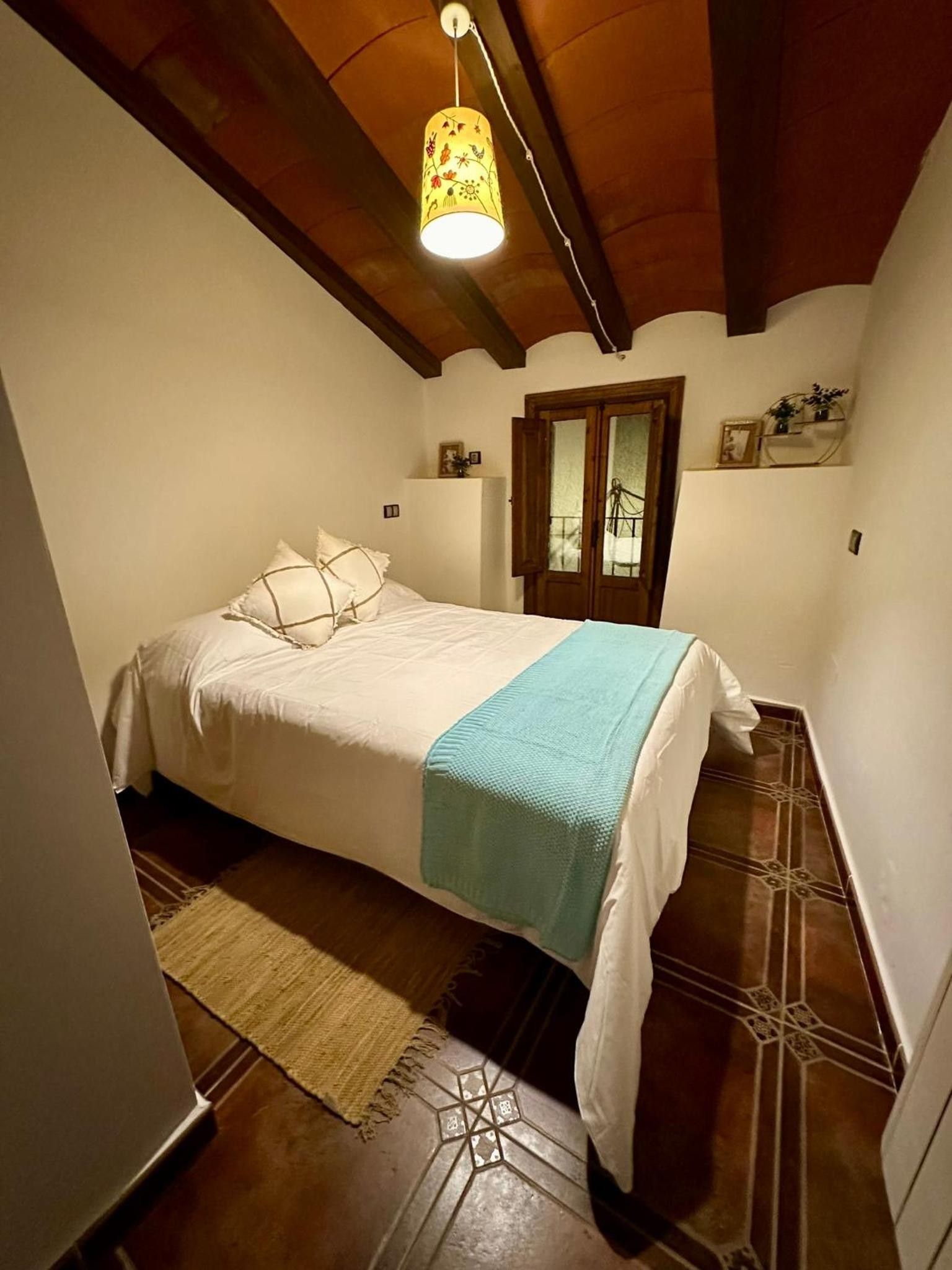 Een slaapkamer met een bed, een hanglamp, een raam en een deur.