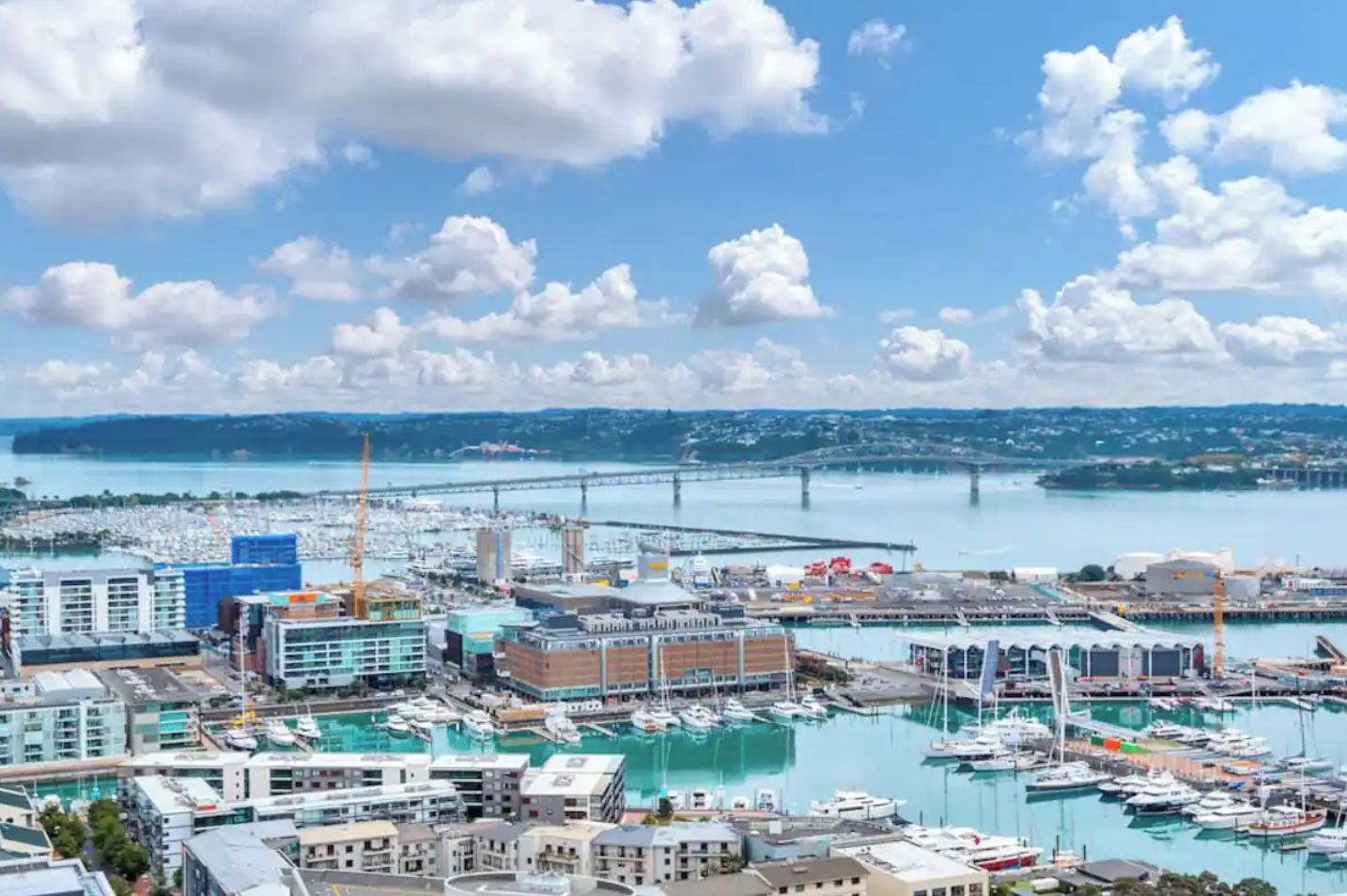 Un port de plaisance avec des bateaux, un pont et des bâtiments en arrière-plan.