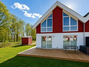A modern two-story house with a red exterior, large windows, and a wooden deck. - Holiday Home in Nordhorn With Swimming Pool (Nordhorn)