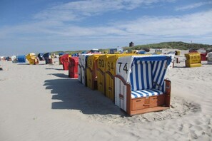 Eine Reihe von Strandliegen mit Nummern, auf einem Sandstrand angeordnet.