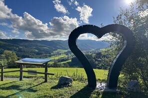 A heart-shaped structure in a natural landscape with a table and a sign, surrounded by greenery and hills. - Holiday home in Turnau with swimming pool (Turnau)