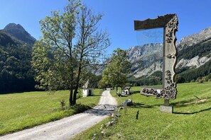 A rural road leading to a mountain pass with a decorative signpost and a clear view of the surrounding landscape.