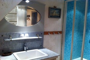 Un bagno con un ampio specchio, un lavandino e una zona doccia.