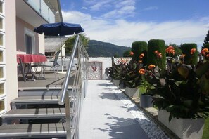 A balcony with a metal railing, a table with a red tablecloth, and potted plants with orange flowers. - Haus Thon Superior Apartment (Bodensdorf)