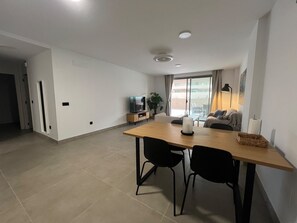 A modern living space with a dining area, a television, and a plant. - Vacation Apartment 'Sotavento Suites' with Sea View, Shared Pool and Wi-Fi (El Médano)