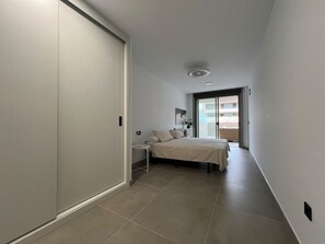A narrow hallway leading to a bedroom with a bed, a nightstand, and a window. - Vacation Apartment 'Sotavento Suites' with Sea View, Shared Pool and Wi-Fi (El Médano)