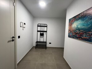 A room with a bed, a painting, and a telephone on the wall. - Vacation Apartment 'Sotavento Suites' with Sea View, Shared Pool and Wi-Fi (El Médano)
