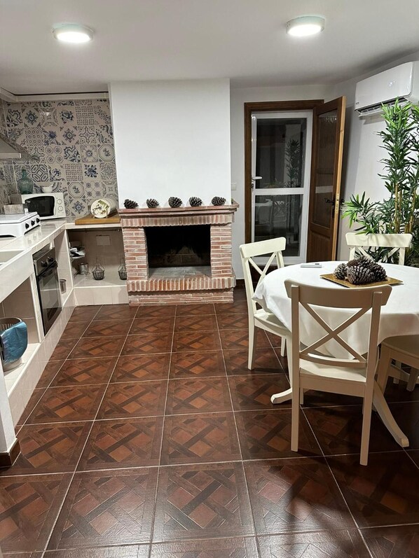 A kitchen with a built-in fireplace, white cabinets, and a dining area with a table and chairs.