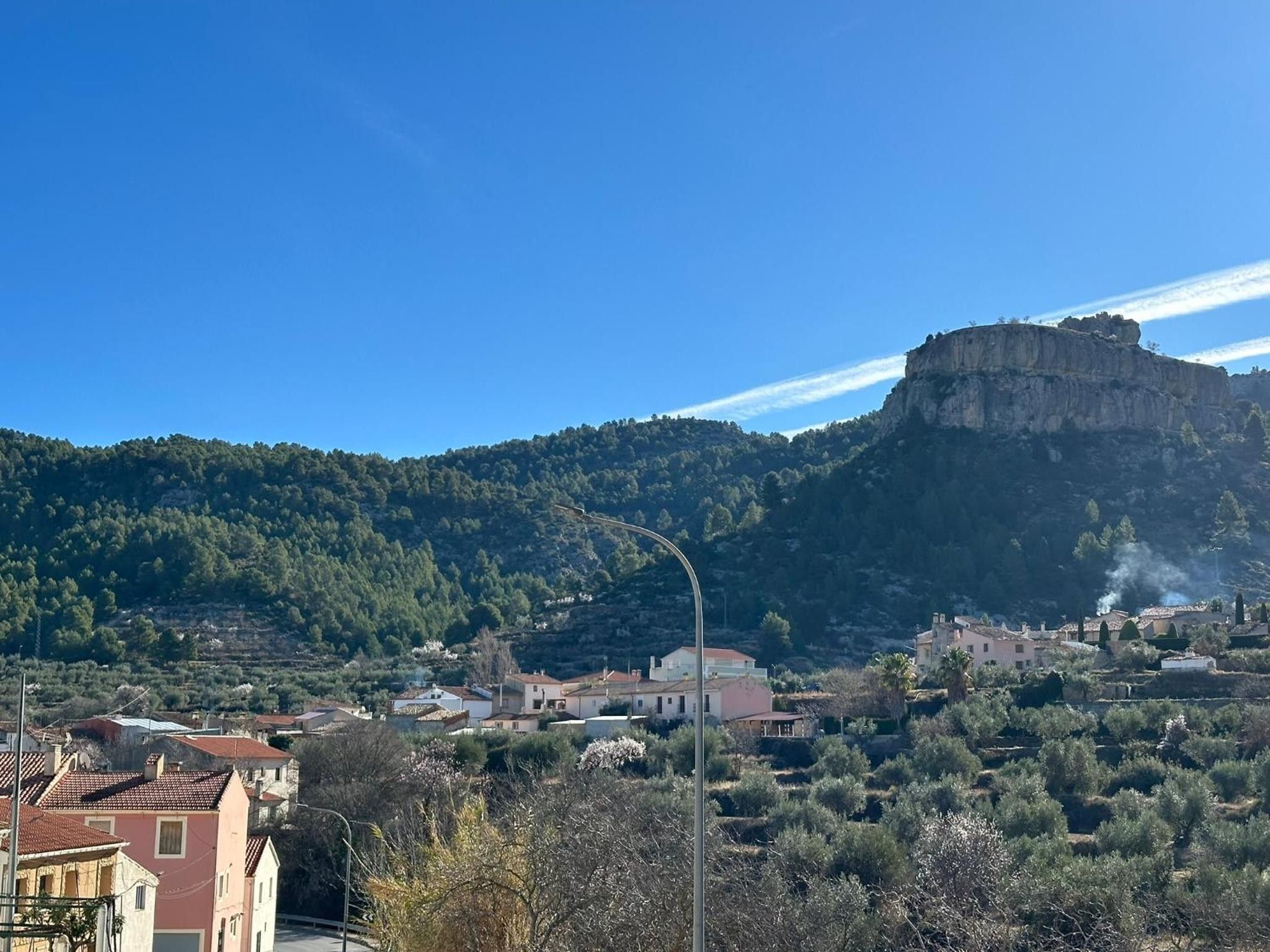 Un pueblo con edificios y un acantilado destacado al fondo.