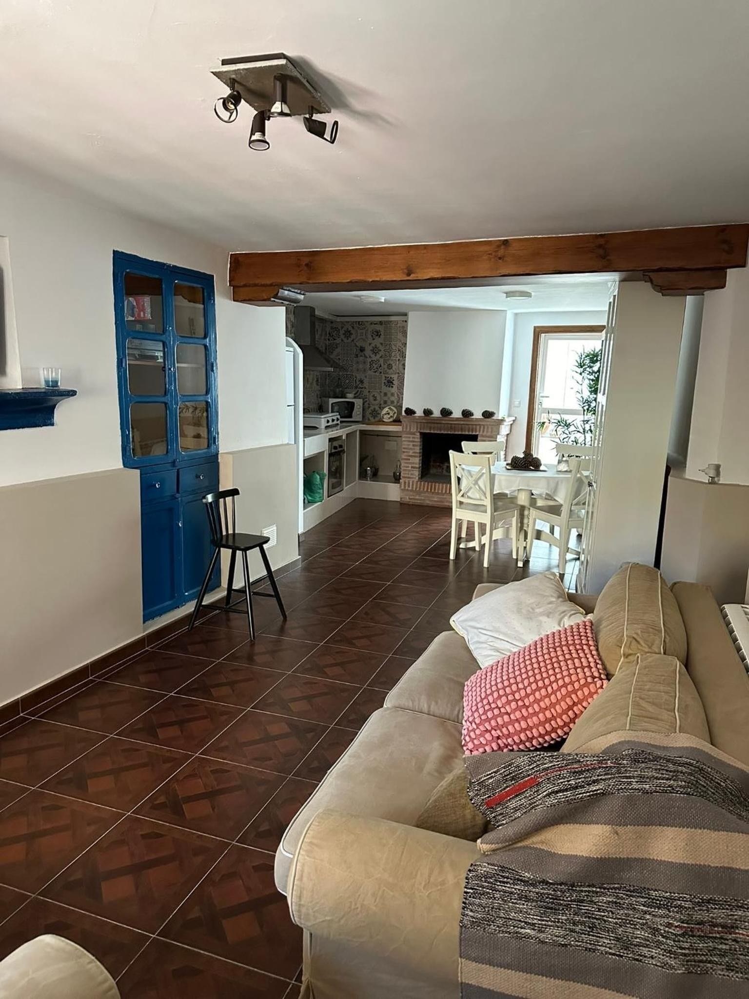 Amplia sala de estar con sofá, mesa de comedor con sillas, cocina al fondo y una puerta azul.