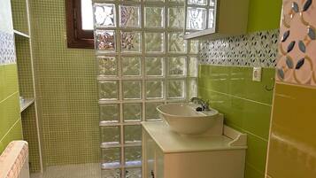 Un baño con ducha, dos lavamanos, inodoro y bidé.