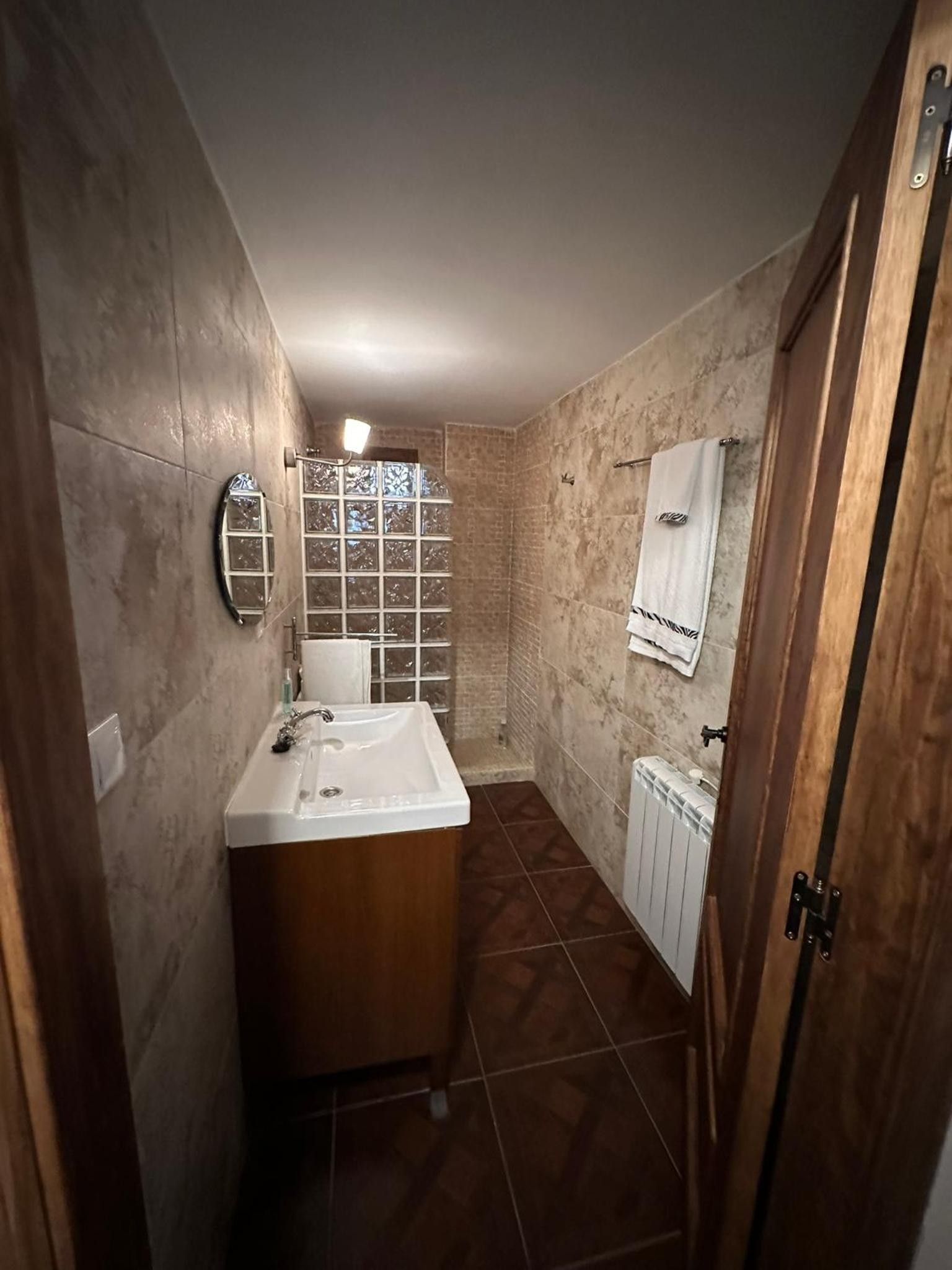 Een badkamer met een houten wastafel, een wit wastafelbakje, een raam met uitzicht en een handdoekhouder.