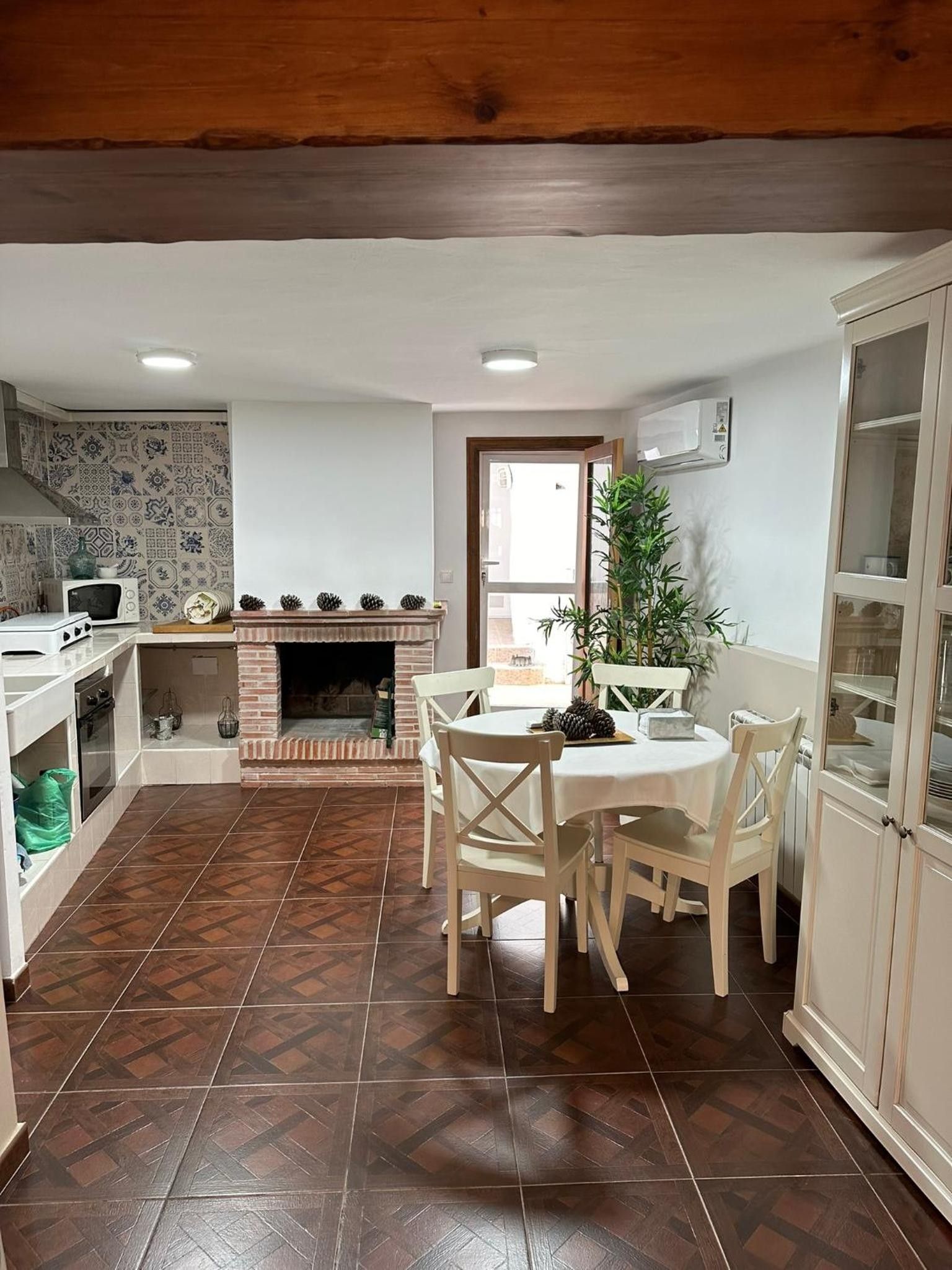 A kitchen with a fireplace, dining table, chairs, and cabinets.
