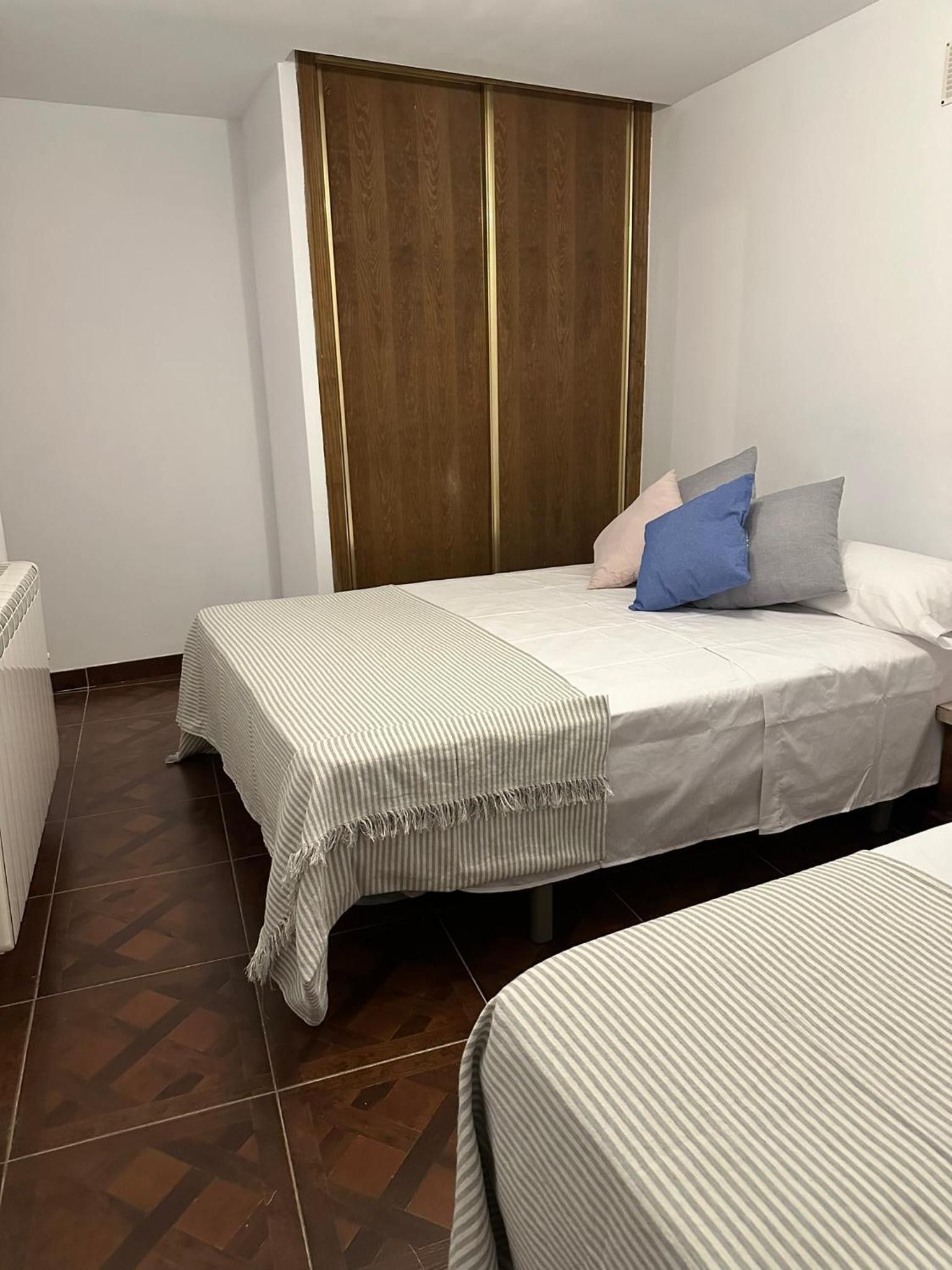 Un dormitorio con dos camas, un armario y un radiador.