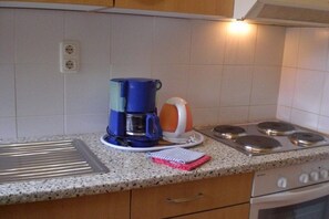 Une cuisine équipée d’une machine à café, d’une bouilloire et d’une cuisinière.