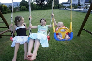 A swing set in a grassy area with a clear sky. - Haus Thon holiday apartment garden view (Bodensdorf)