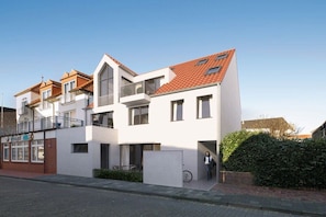 A modern two-story residential building with a balcony, a bicycle parked outside, and a clear sky. - Holiday apartment in Norderney with sauna (Norderney)