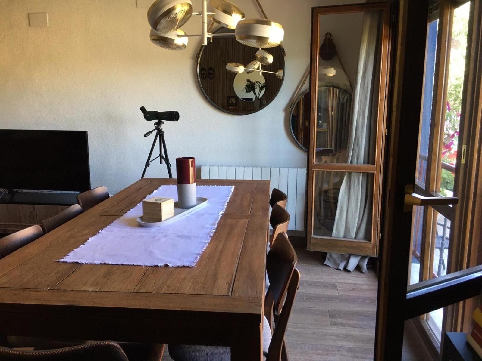 Een eetgedeelte met een houten tafel, stoelen, een statief en een camera op een statief.