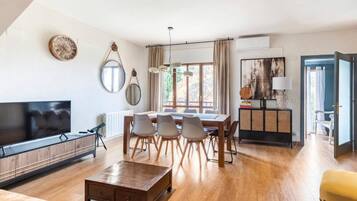 Un salon moderne avec un téléviseur à écran plat, une table à manger en bois et des chaises.