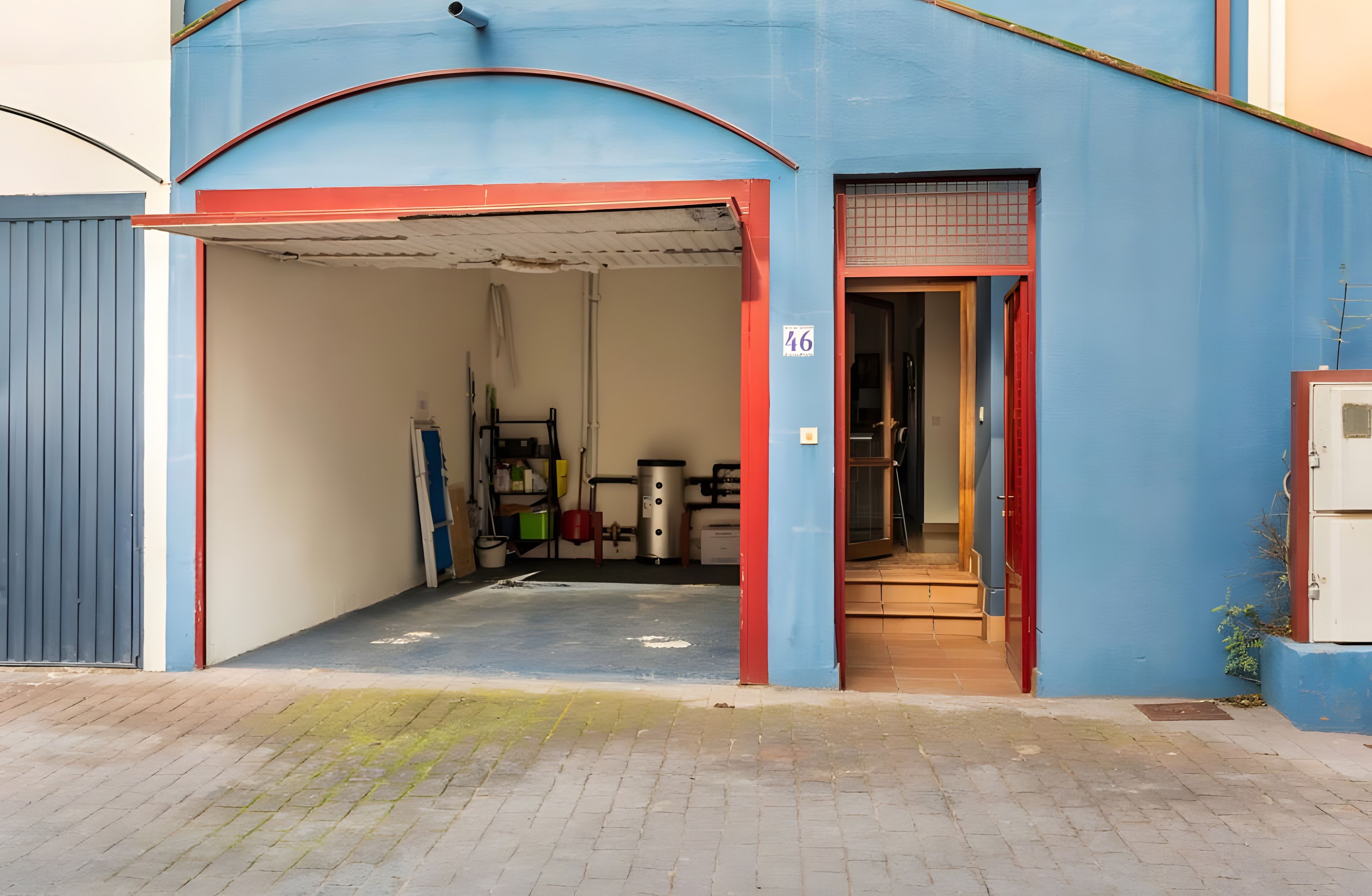 Ein Gebäude mit einer Garageneinfahrt, einem Schild mit der Nummer 46 und einer zur Einfahrt führenden Tür.