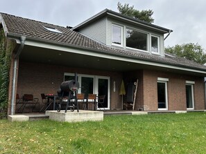 A two-story house with a covered patio area, a barbecue grill, and a brick exterior. - Time out at Lake Lanzer (Basedow)