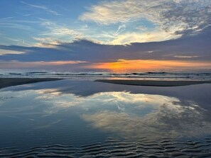 A beach with a sunset, calm water, and a clear sky. - Puik en Duin 5a (Noordwijk)