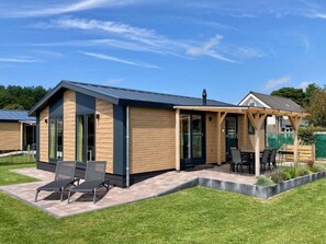 A modern house with a covered patio area, a wooden exterior, and a large window. - Puik en Duin 5a (Noordwijk)