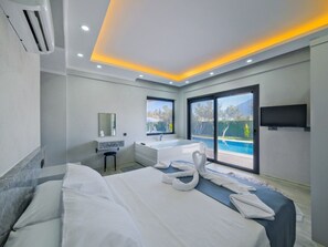 A modern hotel room with a large bed, a bathroom with a bathtub, and a view of a swimming pool. - Villa in Fethiye/mugla With Swimming Pool (Fethiye)