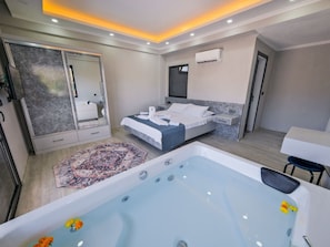 A modern hotel room with a large bed, a separate bathroom with a jacuzzi, and a small sitting area. - Villa in Fethiye/mugla With Swimming Pool (Fethiye)