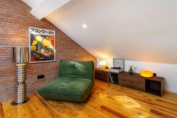 Une pièce de style loft avec un canapé vert, un plancher en bois, un mur en briques et une affiche.
