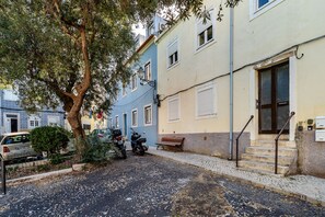 Eine schmale Straße mit parkenden Autos und einem Baum.