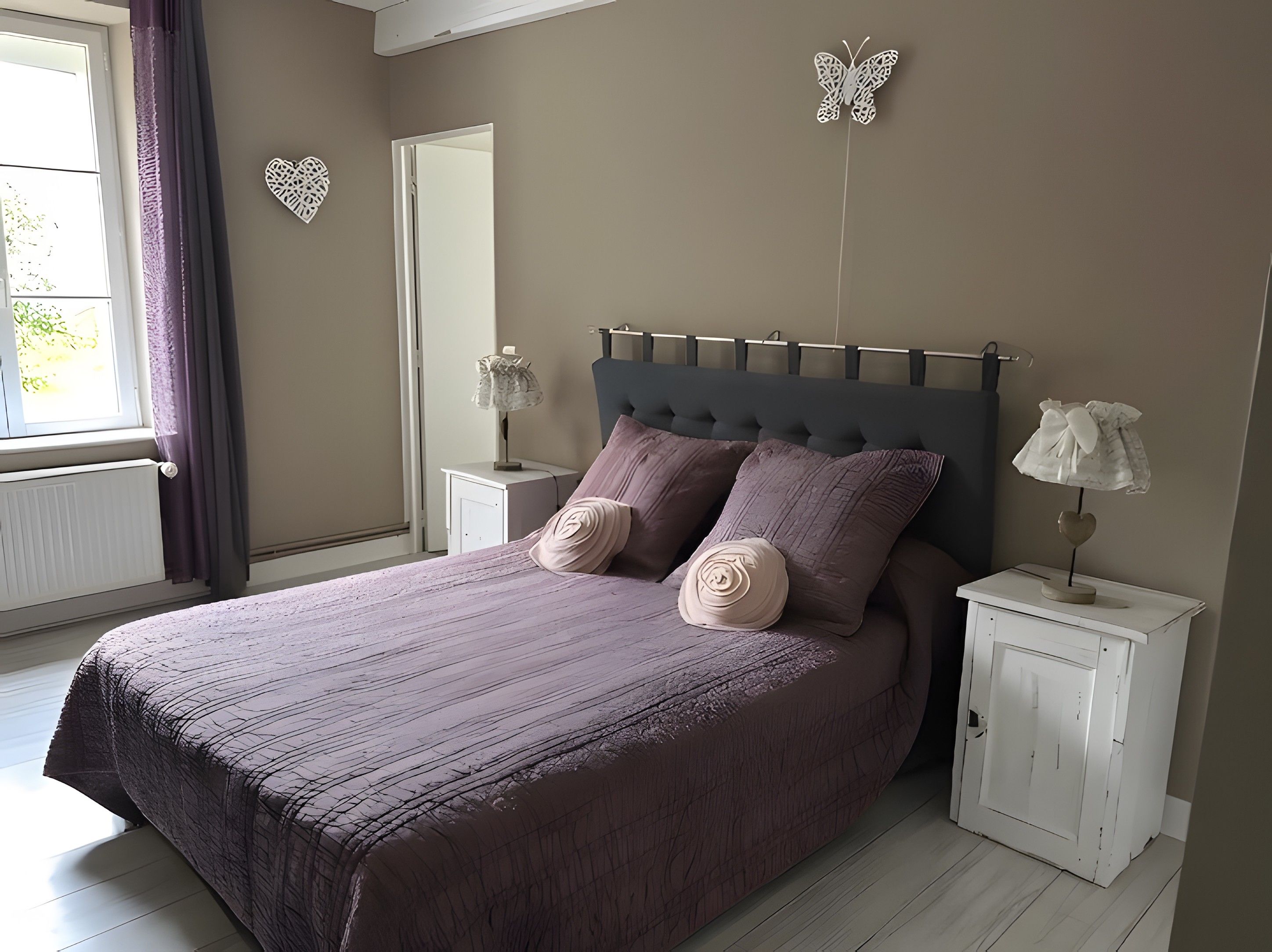 Une chambre à coucher comprenant un lit, des tables de chevet, une lampe et des œuvres d’art décoratives au mur.